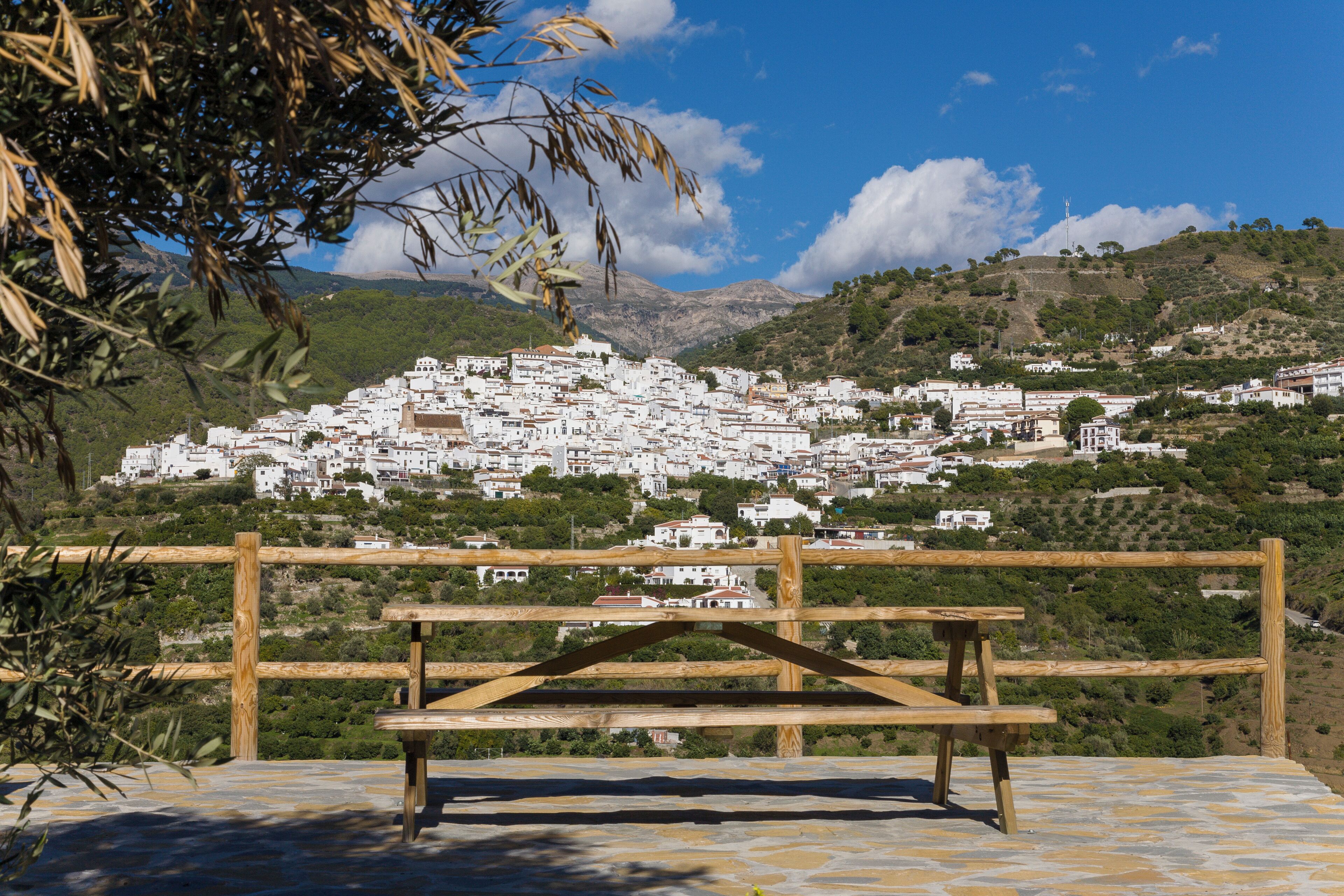 Un banco de madera con vistas a un pueblo en una colina con edificios blancos.