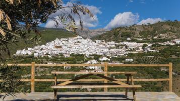 Un banco de madera con vistas a un pueblo en una colina con edificios blancos.