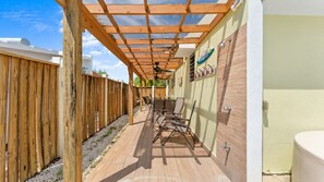 A covered outdoor patio with a wooden pergola, a seating area with chairs, and a wall with a sign. - Casa Isabel at Puerto Bahia | Pool & Steps to Beach (Rincón)