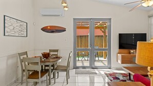A dining area with a table and chairs, a television, and a sliding glass door leading to an outdoor area.