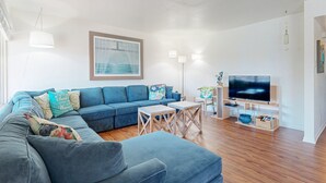 Een moderne woonkamer met een blauwe bank, een flatscreen televisie en een schilderij van een brug.