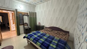 A bedroom with a bed, a dresser, a mirror, and a door leading to another room.