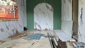 Une pièce en construction, avec des murs apparents, un plafond en bois et des matériaux de construction éparpillés.