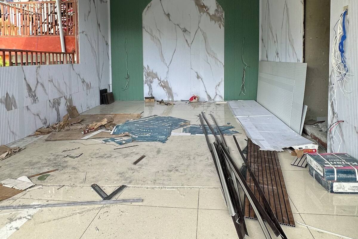 A room under construction with exposed walls, a wooden ceiling, and construction materials scattered around.