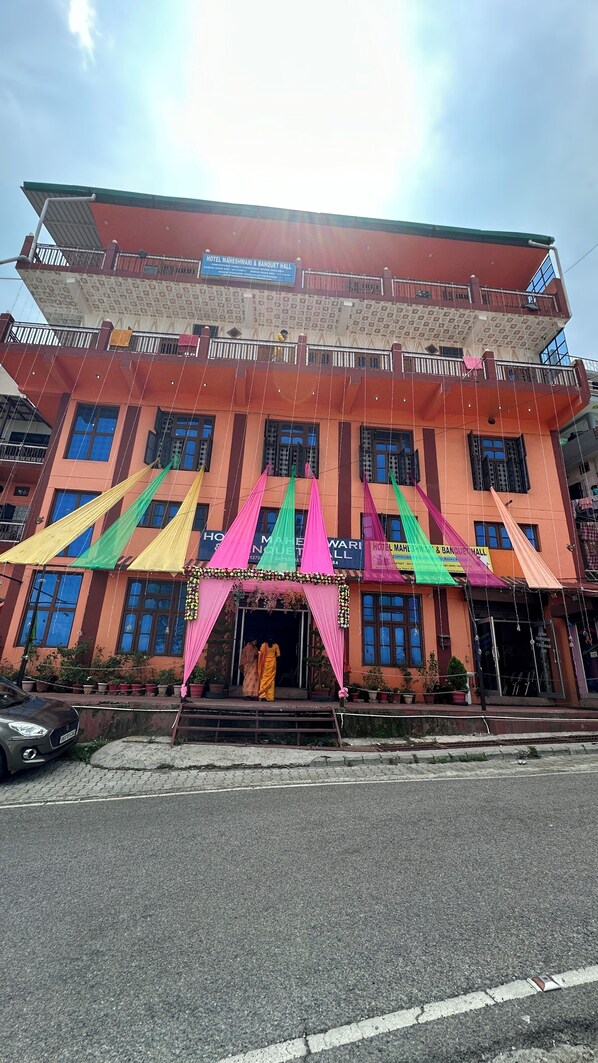 A hotel with a red facade, multiple windows, and colorful awnings.