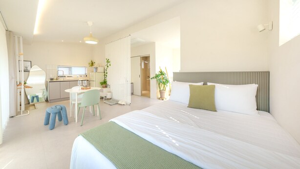 A modern hotel room with a large bed, a desk, and a kitchenette. - Gyeongju Daol Dokchae Pension (Gyeongju)