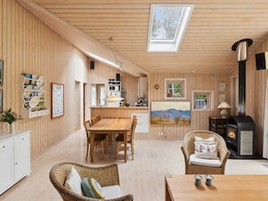 A wooden interior with a dining area, kitchen, and a fireplace.
