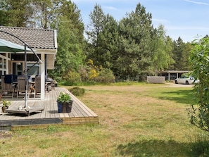 A wooden deck with outdoor furniture, a covered patio, and a view of a forested area. - "Tyyne" - 250m from the sea by Interhome (Sjællands Odde)