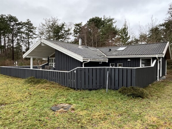 Relax on the covered porch amidst a serene, grassy setting.