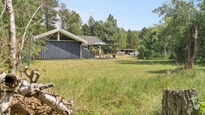A rural property with a wooden cabin, a covered outdoor seating area, and a car parked in the background. - "Tyyne" - 250m from the sea by Interhome (Sjællands Odde)