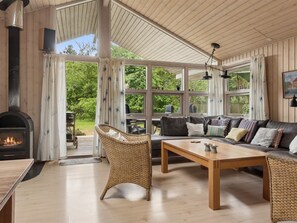 A cozy living room with a fireplace, large windows, a sofa, and a dining area. - "Tyyne" - 250m from the sea by Interhome (Sjællands Odde)