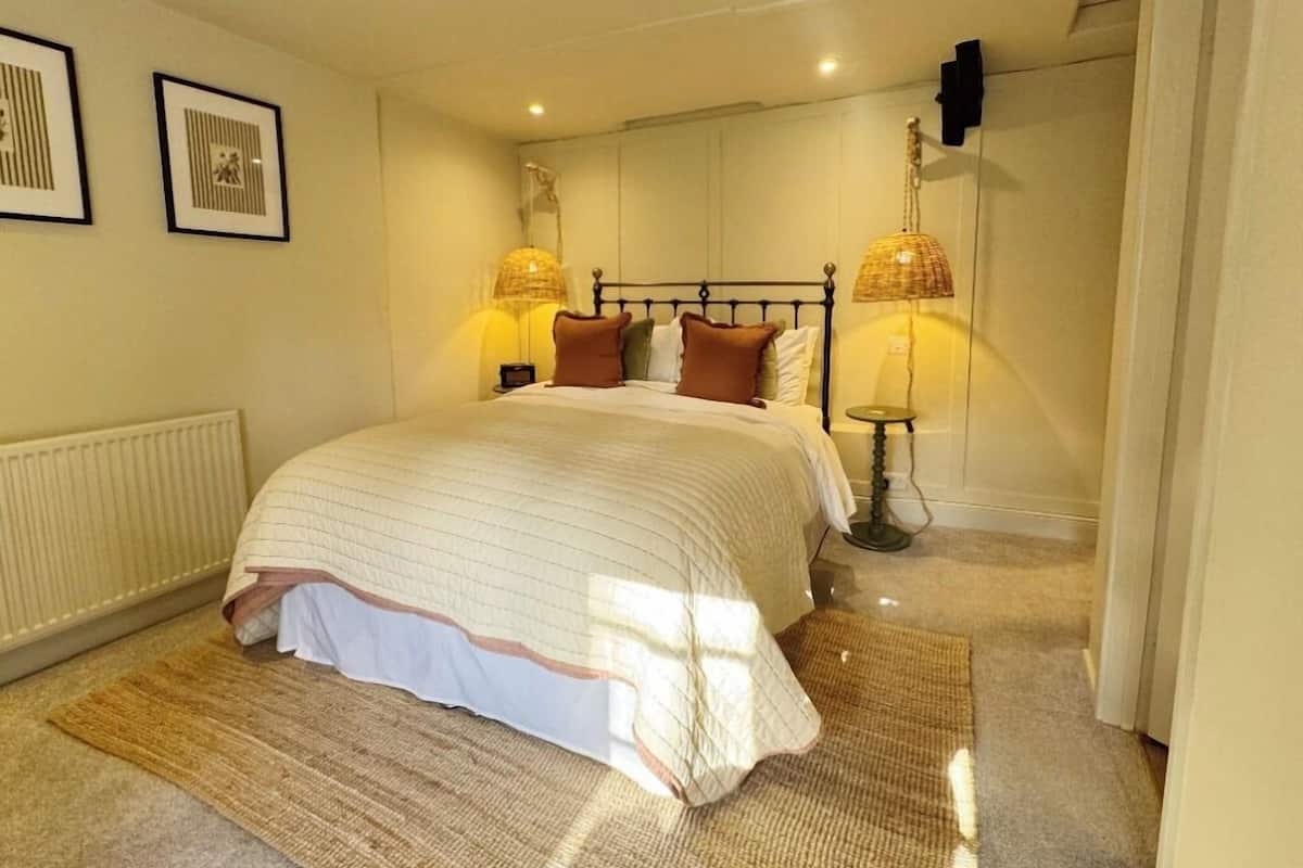 Un dormitorio ordenado con una cama grande, dos lámparas de noche y un radiador.