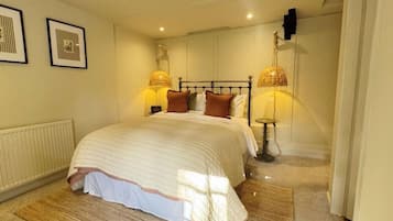 A neatly arranged bedroom with a large bed, two bedside lamps, and a radiator.