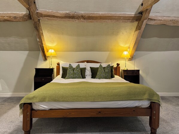A wooden bed with a green blanket, two bedside lamps, and a headboard. - The Neeld Arms (Chippenham)