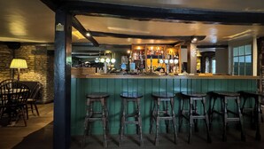 A bar area with wooden stools, a counter with taps, and shelves with bottles. - The Neeld Arms (Chippenham)