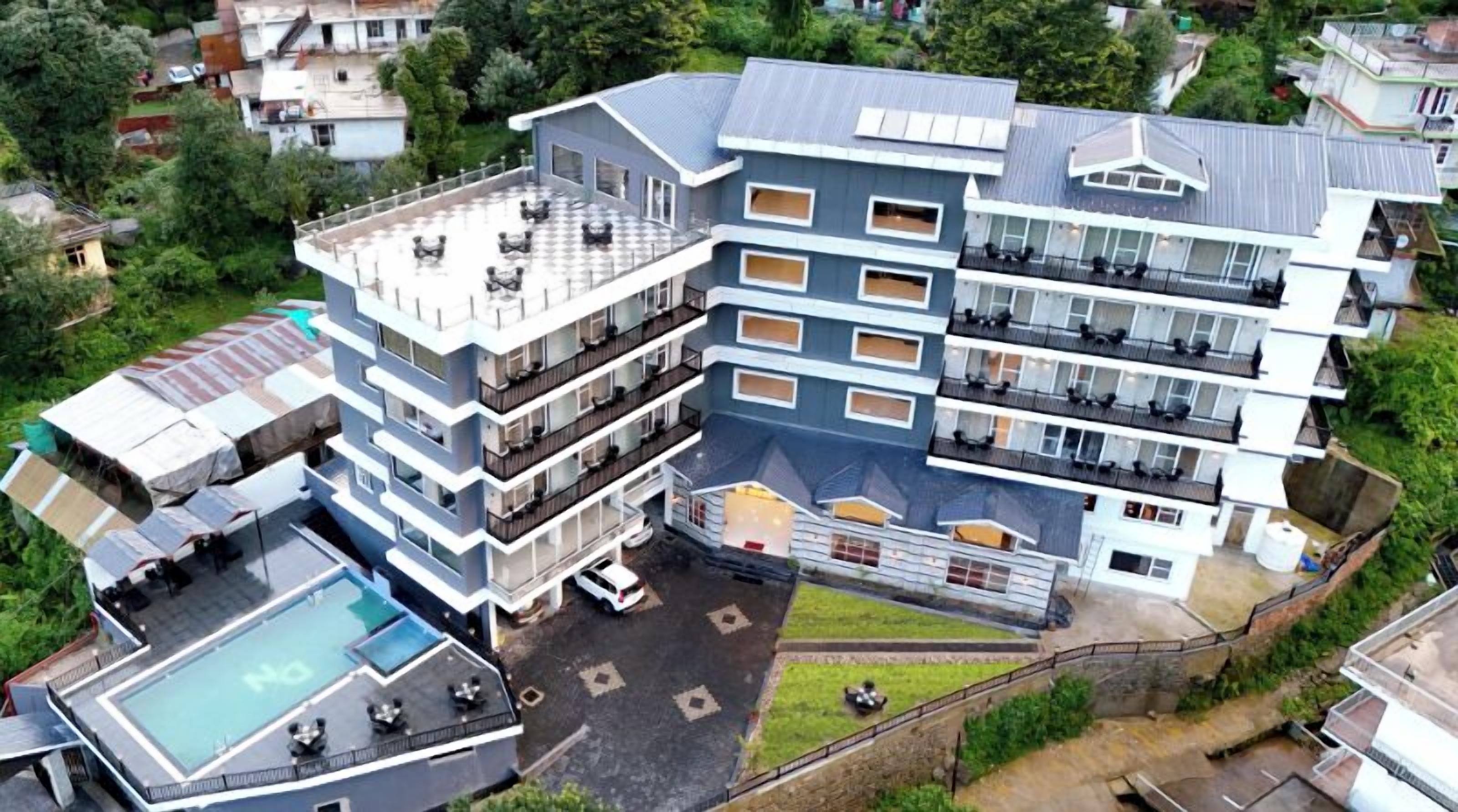A multi-story hotel with a rooftop pool, balconies, and a central courtyard.