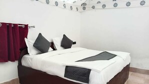 Een opgemaakt bed met een donker hoofdbord, witte lakens en twee kussens.