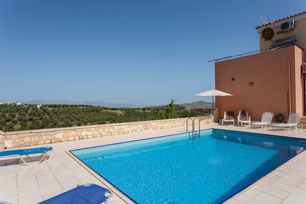 A swimming pool with lounge chairs and a view of the countryside. - Hillside Seaview Apartment (Chania)