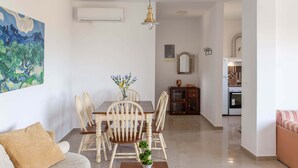 Un comedor con una mesa y sillas de madera, un jarrón con flores y un cuadro en la pared.