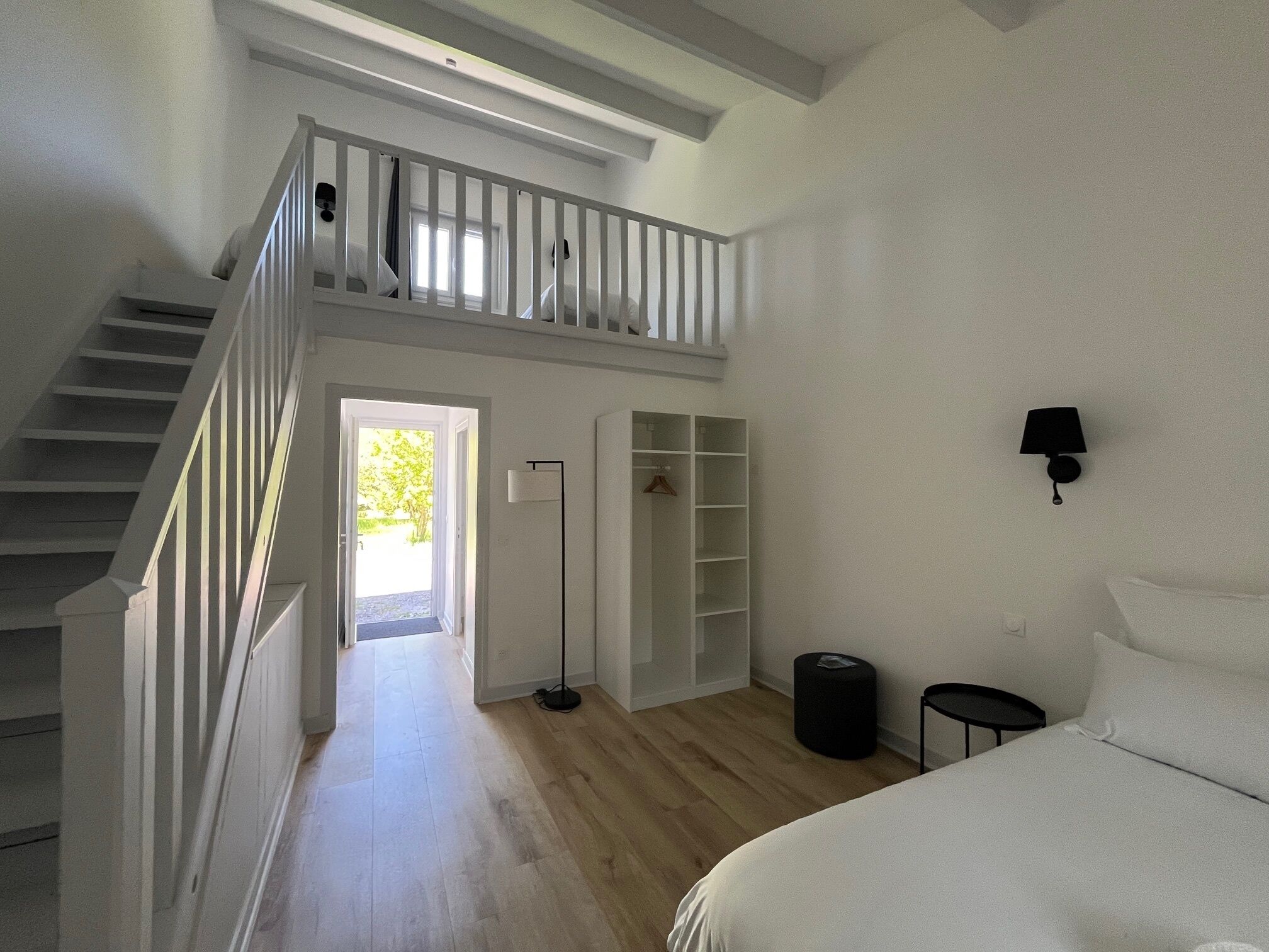 A bedroom with a bed, a nightstand, a closet, and a staircase leading to an upper level.