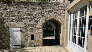 A stone archway leading to a building with a white door and a windowed entrance. - Le moulin de barette (Blavozy)