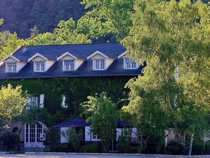 A building with a dark roof, multiple windows, and a parking sign. - Le moulin de barette (Blavozy)