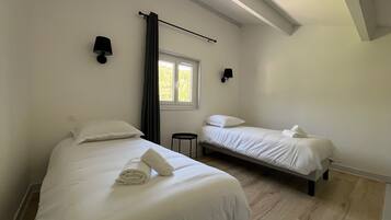 A bedroom with two beds, a window, and a curtain.