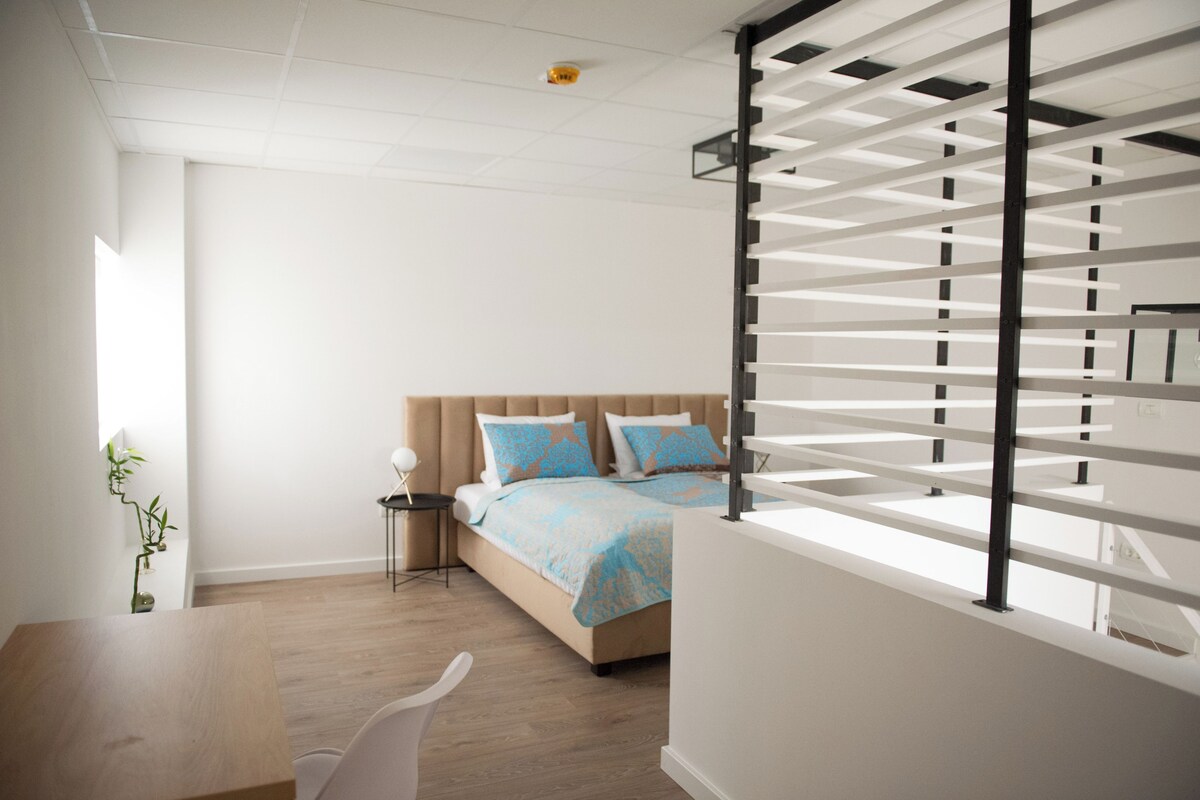 Une chambre à coucher moderne avec un lit, une table de chevet et une fenêtre avec des stores.