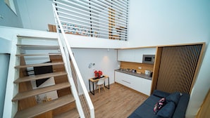 A modern apartment with a staircase leading to a loft bedroom, a kitchenette, and a living area with a sofa. - FRIENDS RESIDENCE (Timisoara)