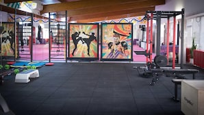 A gym with various exercise equipment, colorful murals, and a tiled floor. - FRIENDS RESIDENCE (Timisoara)