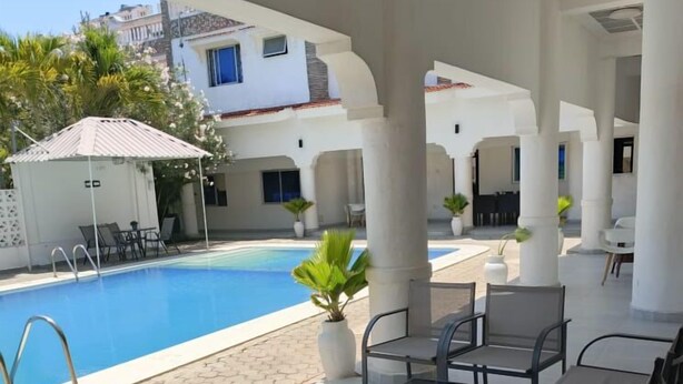 A poolside area with a clear view of the pool, surrounded by white columns and covered seating. - Chamiachi Hotel and Luxury Apartments  (Mombasa)
