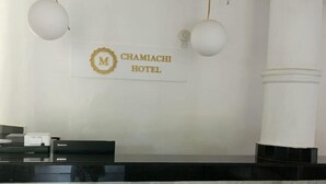 A reception desk with a marble countertop, a logo for Chamiachi Hotel, and two hanging spherical light fixtures. - Chamiachi Hotel and Luxury Apartments  (Mombasa)