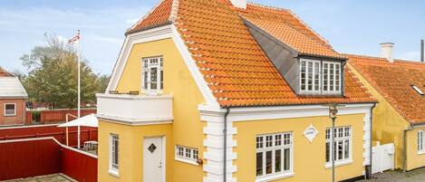 A yellow building with a red-tiled roof, white trim, and a small porch.