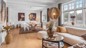 Ein geräumiges Wohnzimmer mit Holzboden, einer Couch, einem Couchtisch und einem Essbereich mit Tisch und Stühlen.