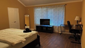 Ein Hotelzimmer mit einem Bett, einem Fernseher, einem Schreibtisch mit Stuhl und einem Fenster mit Vorhängen.