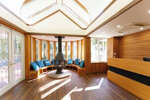 A modern interior with a central fireplace, wooden paneling, and large windows.