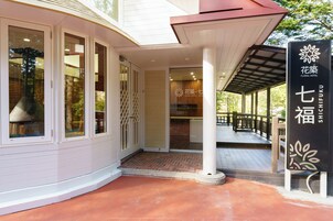 A hotel entrance with a covered porch, a signboard, and a brick pathway leading to the door.