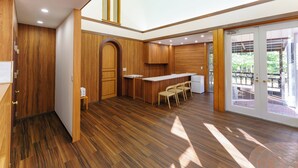 Una cocina moderna con armarios de madera, una isla integrada con taburetes de bar y un cerramiento de vidrio corredero que da a un patio exterior.
