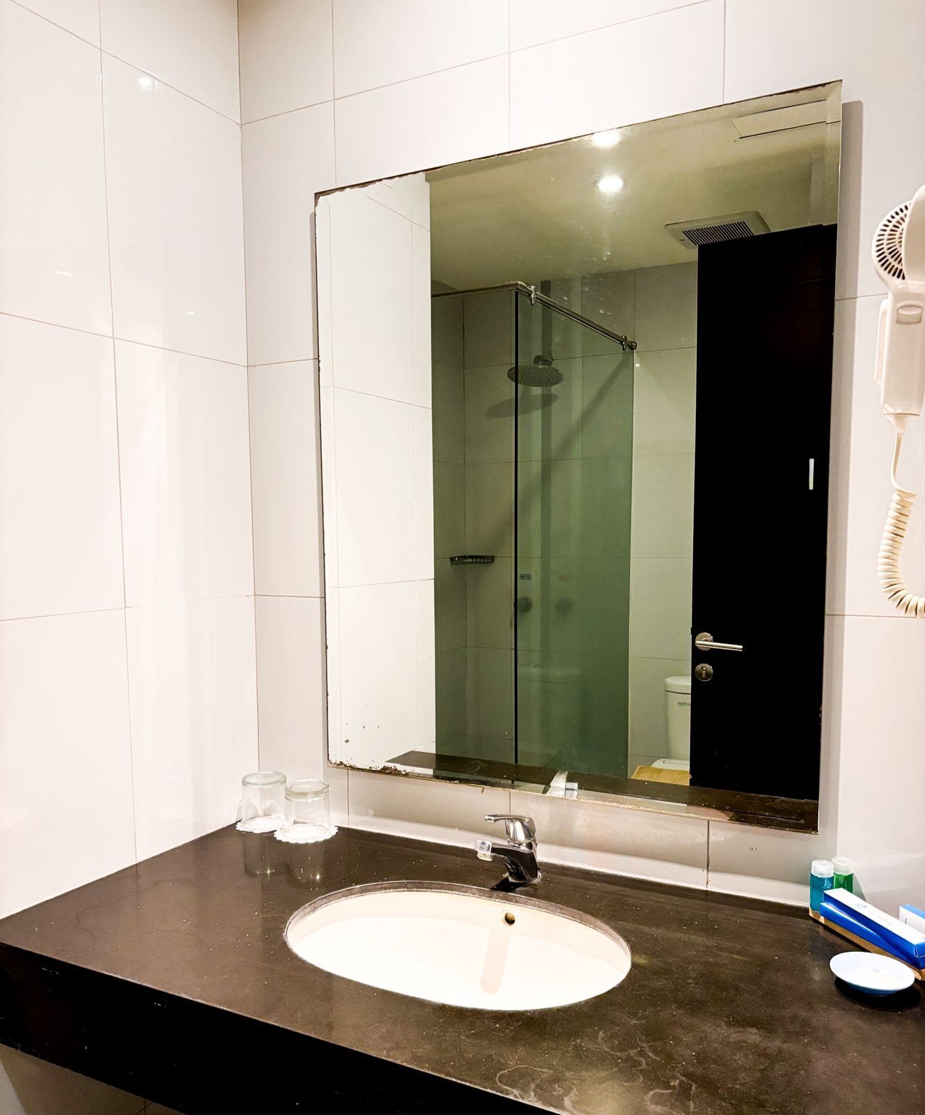 Un baño con un espejo grande, un lavabo y una ducha.