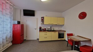 A compact kitchen with a red refrigerator, yellow cabinets, a sink, and a clock on the wall. - Modern apartment Peter in Bärenstein for 2 persons (Bärenstein)