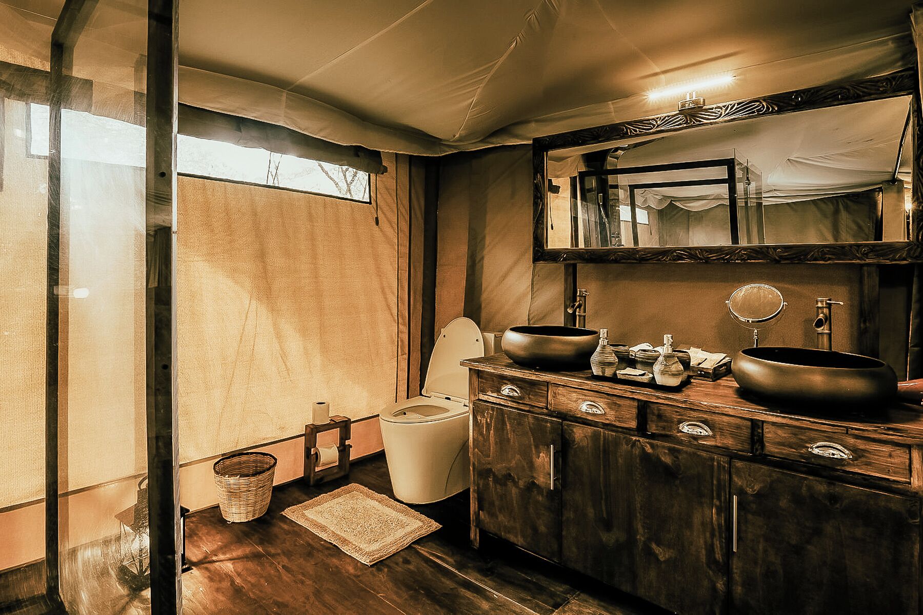 A bathroom with a wooden vanity, two sinks, a mirror, and a toilet.