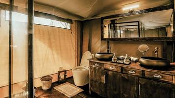A bathroom with a wooden vanity, two sinks, a mirror, and a toilet.