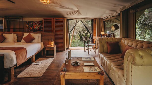 Acomodação em tenda com cama, sofá e área de trabalho.