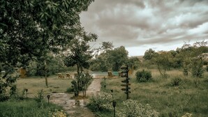 Caminho de pedra que leva a uma área de piscina com espreguiçadeiras e um sinalizador indicando direções.