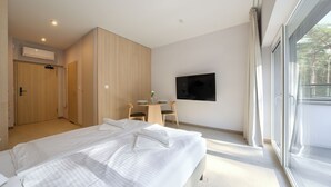 Una habitación de hotel moderna con una cama grande, una pequeña mesa con sillas, un televisor de pantalla plana montado en la pared y un ventanal con vistas al exterior.