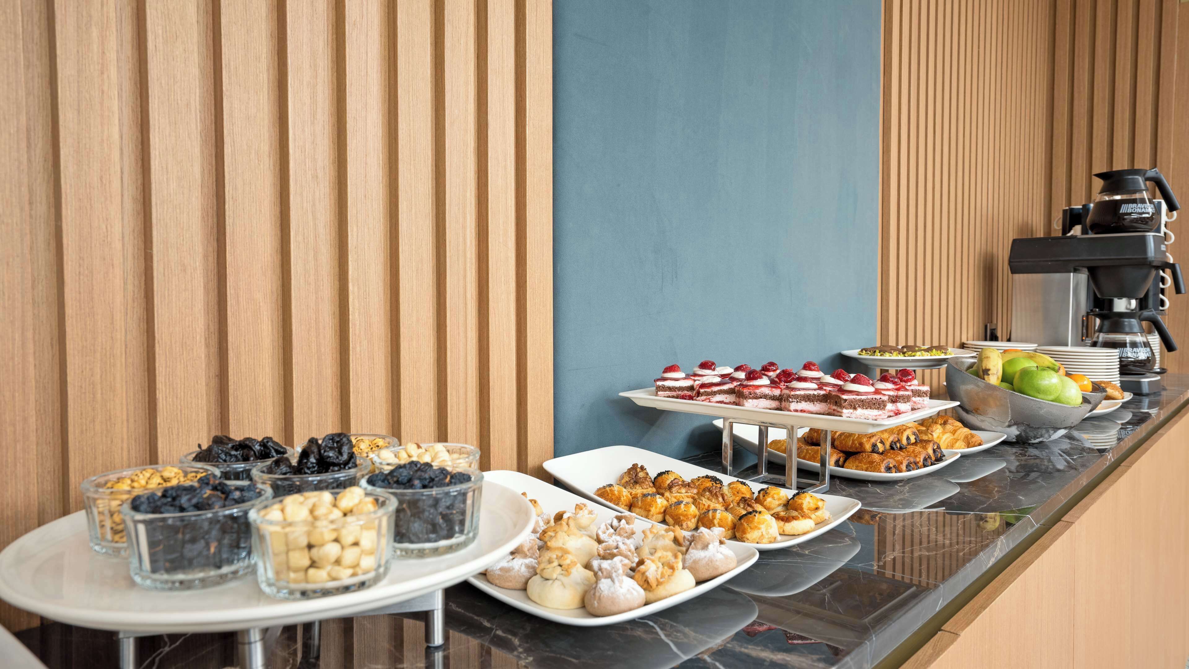 Een buffet met diverse gerechten, waaronder gebak, fruit en desserts.