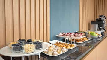 Un buffet proposant une variété de plats, notamment des pâtisseries, des fruits et des desserts.