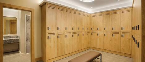 A modern locker room with wooden lockers, a bench, and a mirror.