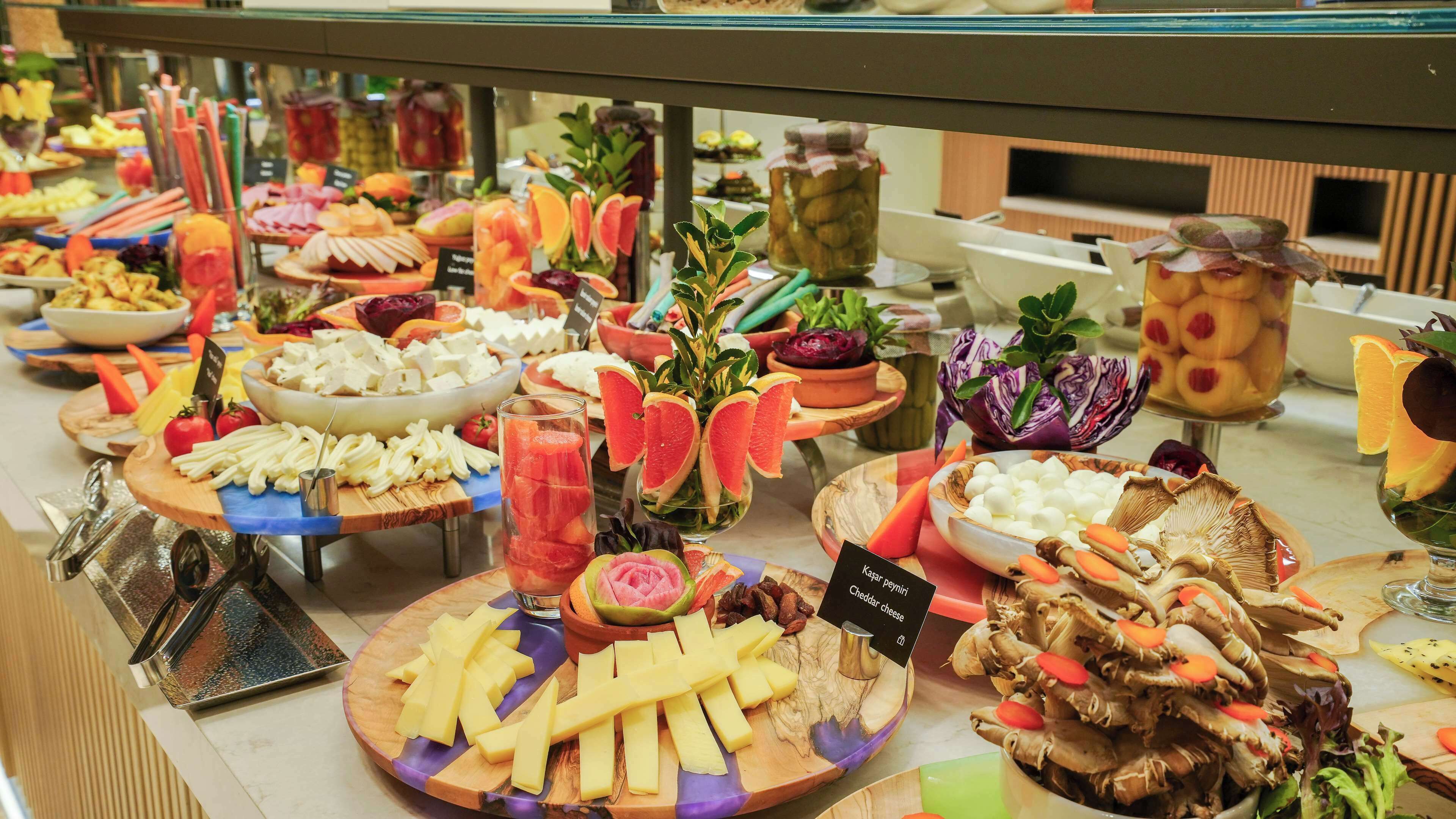 Un bufé con diversos alimentos, incluyendo queso, frutas y verduras.