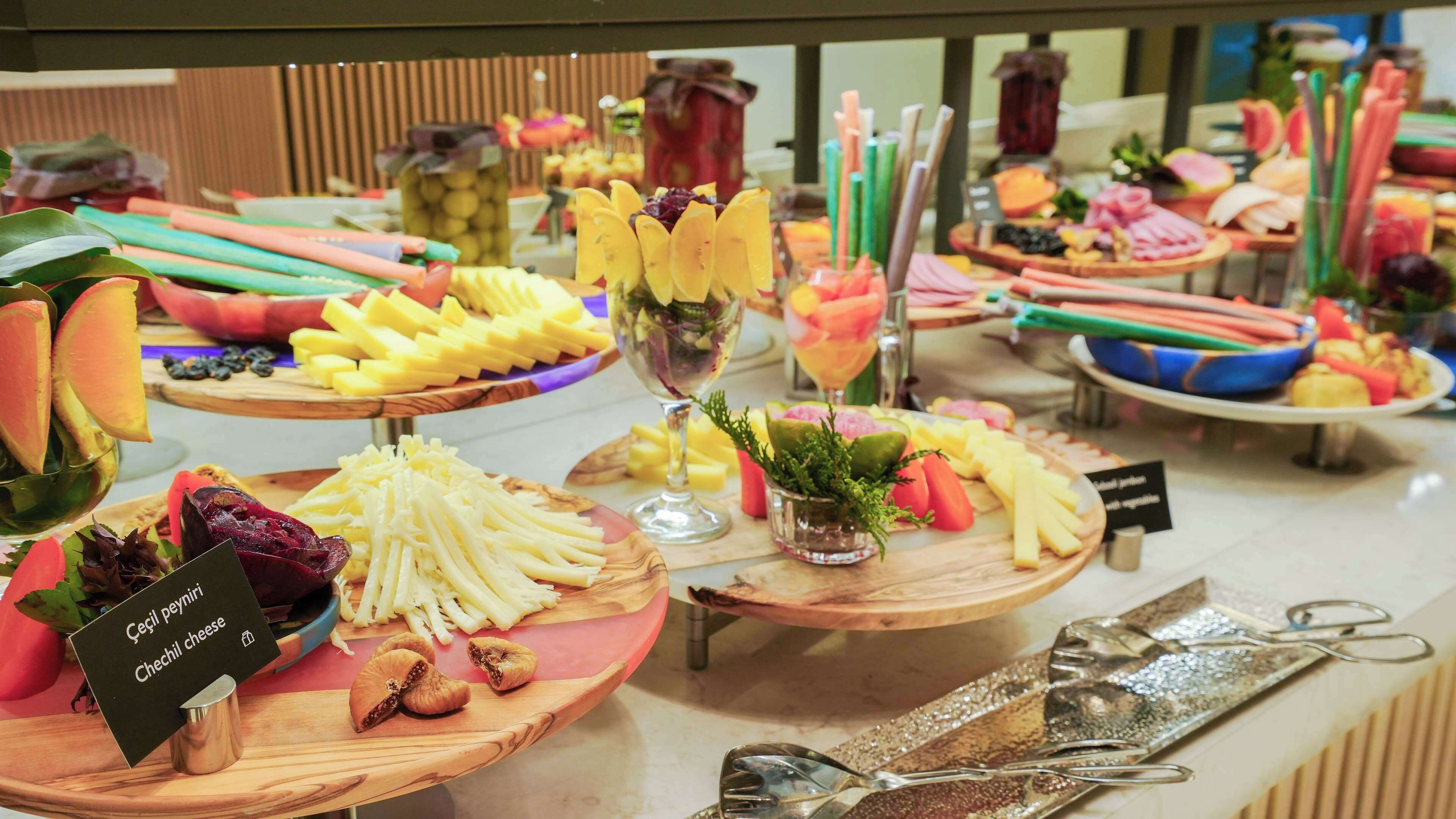 Buffet com diversas opções de comida, incluindo frutas, queijos e legumes.